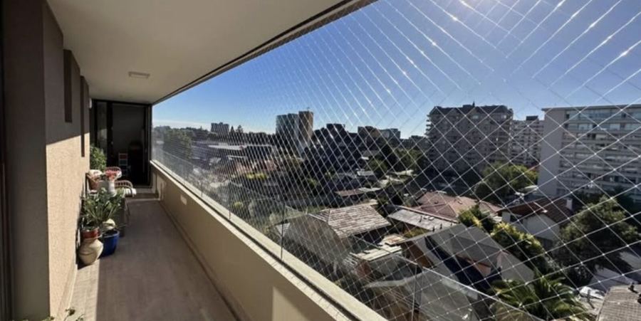 Balcón con cierre de malla de seguridad y vista a la ciudad
